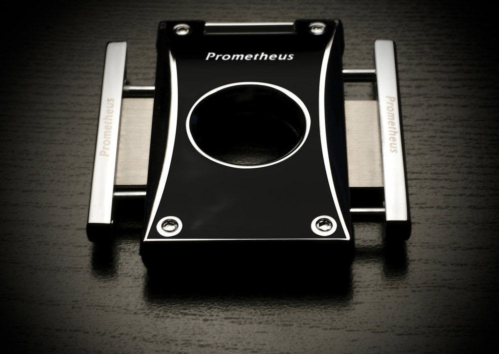 A black and chrome metal cigar cutter from the Prometheus brand of accessories. The sides of the cutter come out and are squeezed to create the sleek and precise cut. The design is modern and good-looking. 