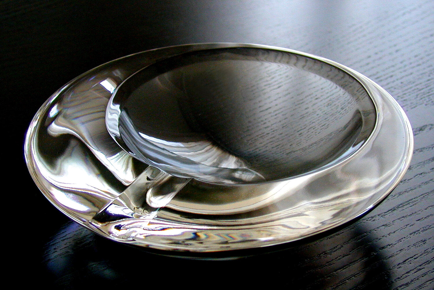 Sleek circular glass ashtray with a modern look. The ashtray has a single cigar ledge. The brand is Prometheus. 